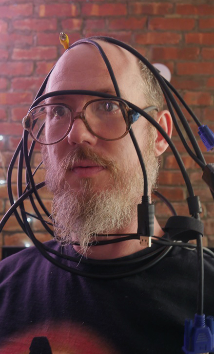 Photo of Andrei Jay with various cables draped over their head